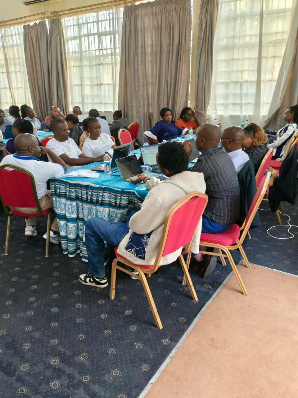 Participants working together at laptops around tables during a workshop